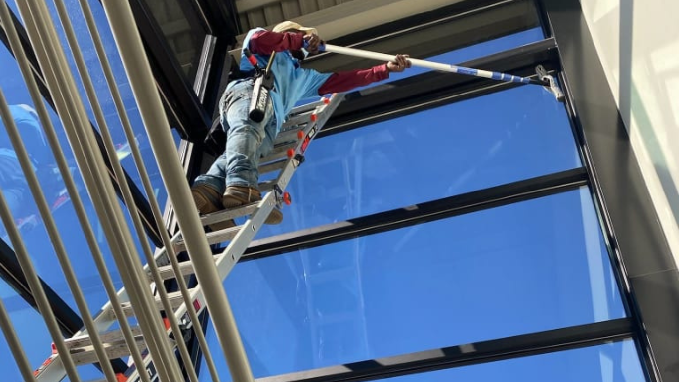 Window Hero professional cleaning windows at hospital interior.