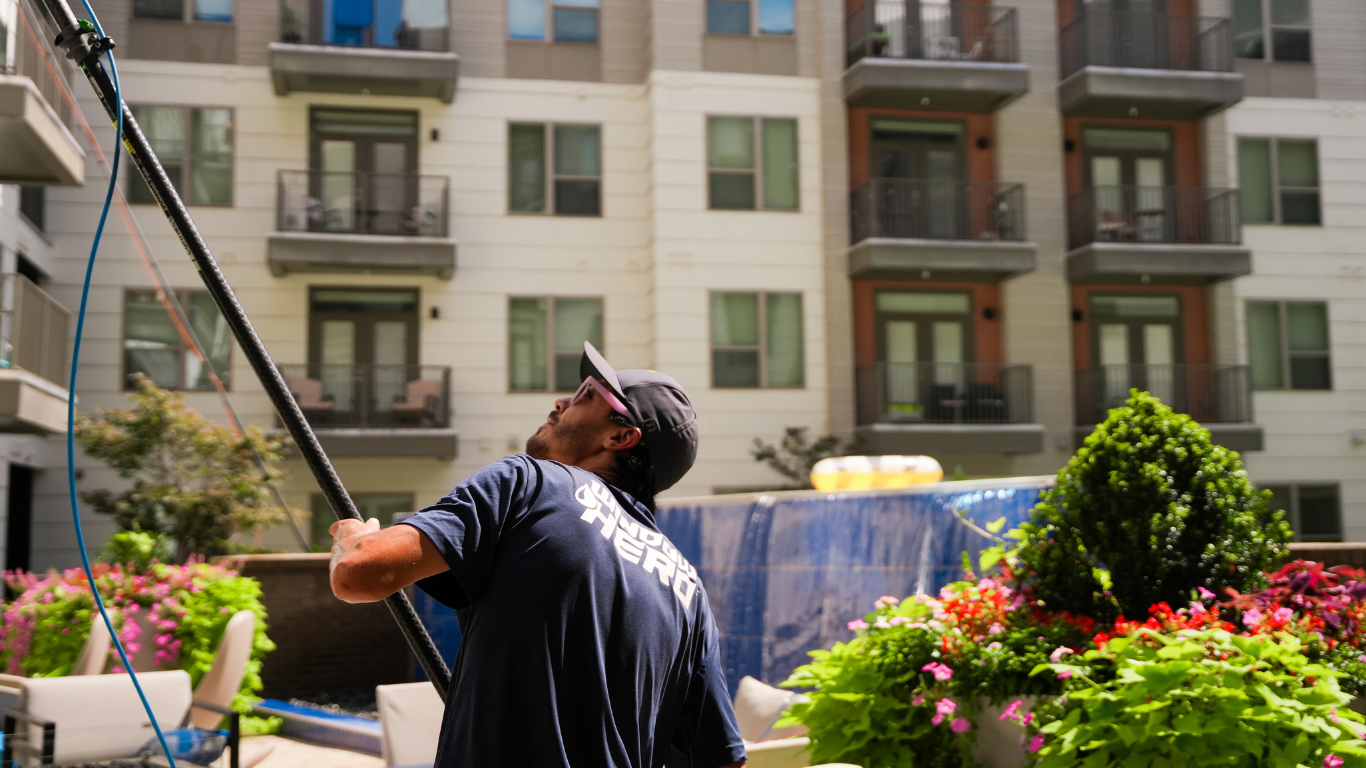 Window Hero professional cleaning a window at apartment.