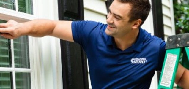 A Window Hero professional holds onto his ladder as he gently cleans a home's window.