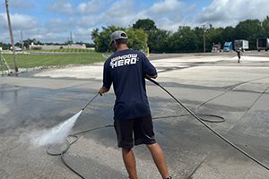 A Window Hero professional pressure washing a concrete surface.