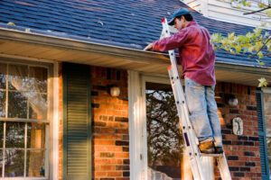 man cleaning gutters on ladder